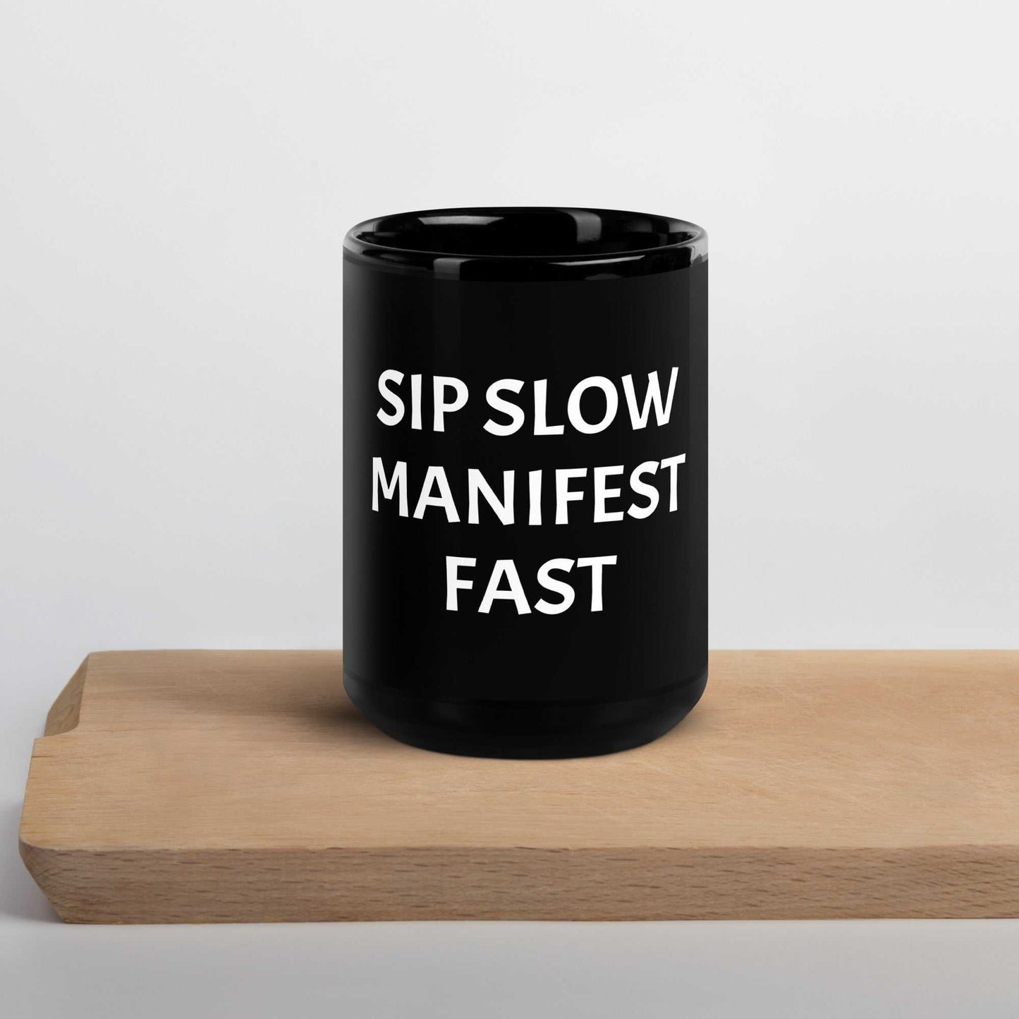 Black glossy mug with "Sip slow, manifest fast" affirmation and high-gloss finish