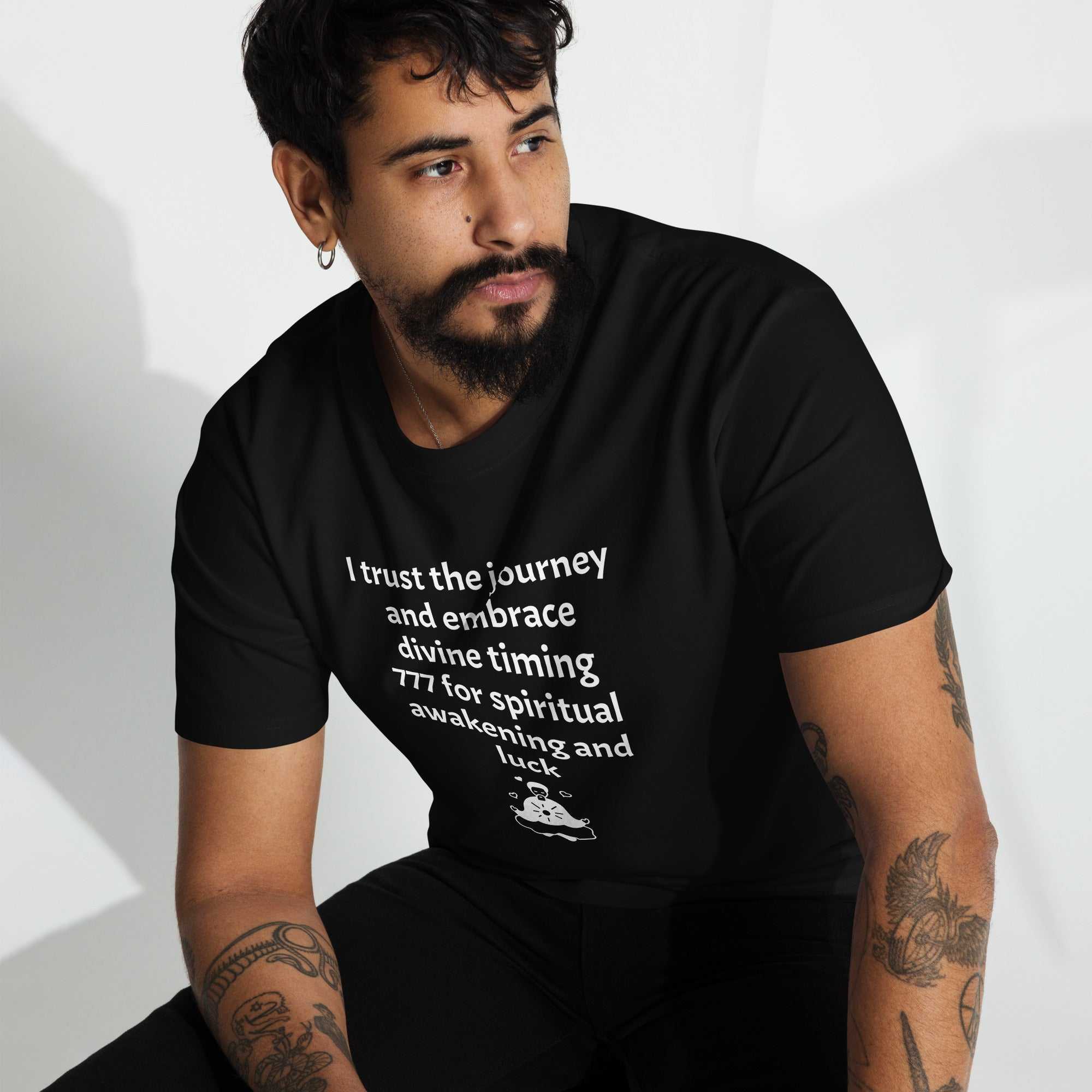 Man wearing black men's premium heavyweight tee with spiritual text design sitting and looking away